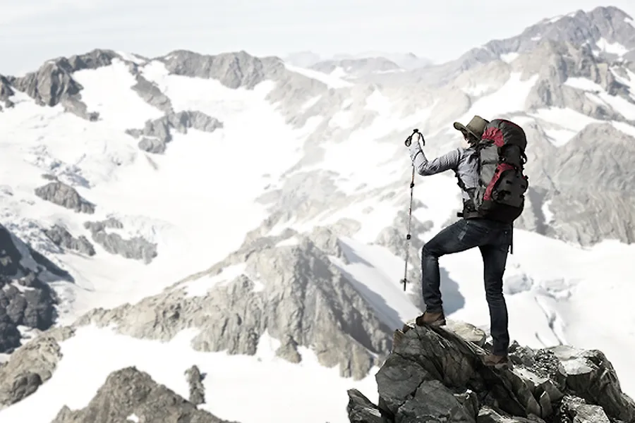 Mountain climber on a peak looking across the range.